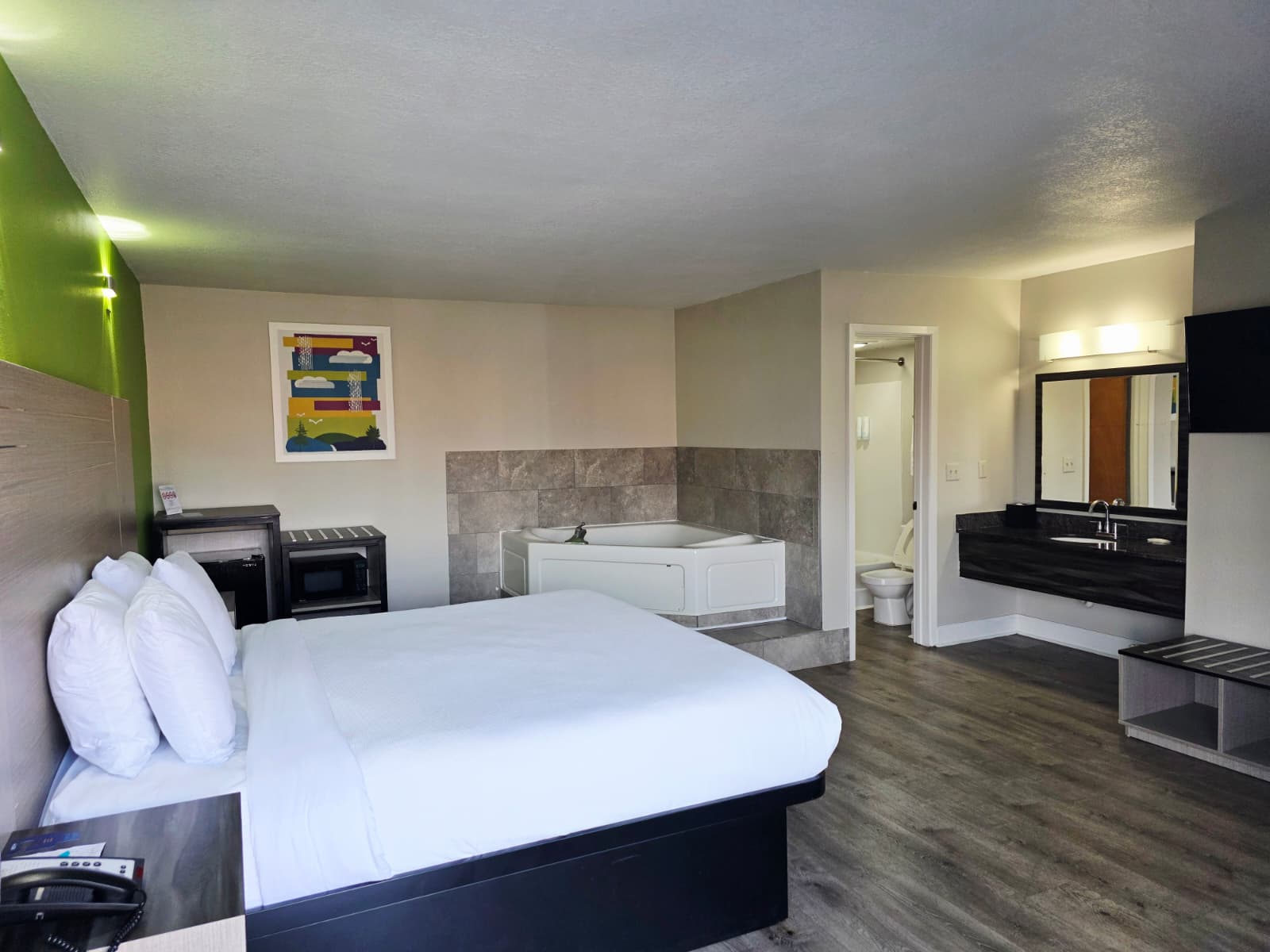 King with Jacuzzi Non-Smoking guest room with a king bed, an in-room jacuzzi tub and a vanity outside the bathroom